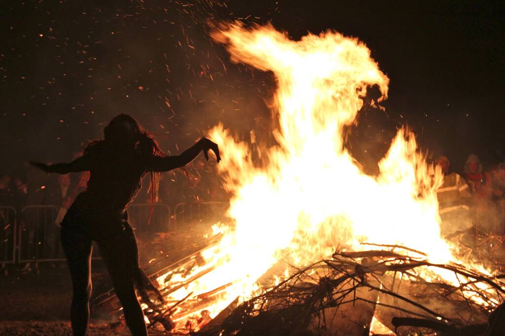 Woman dancing joyfully in front of a bonfire during a Beltane celebration