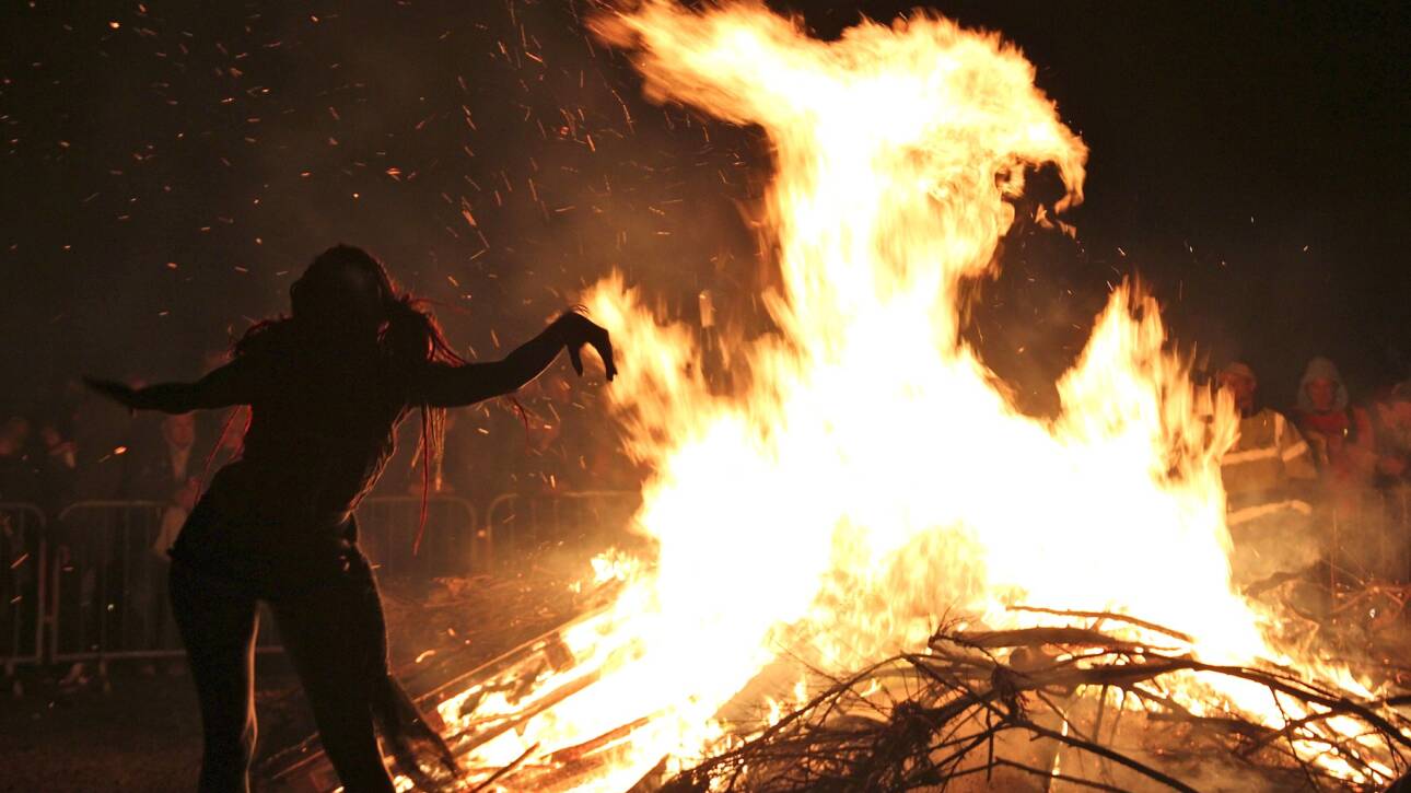Woman dancing joyfully in front of a bonfire during a Beltane celebration