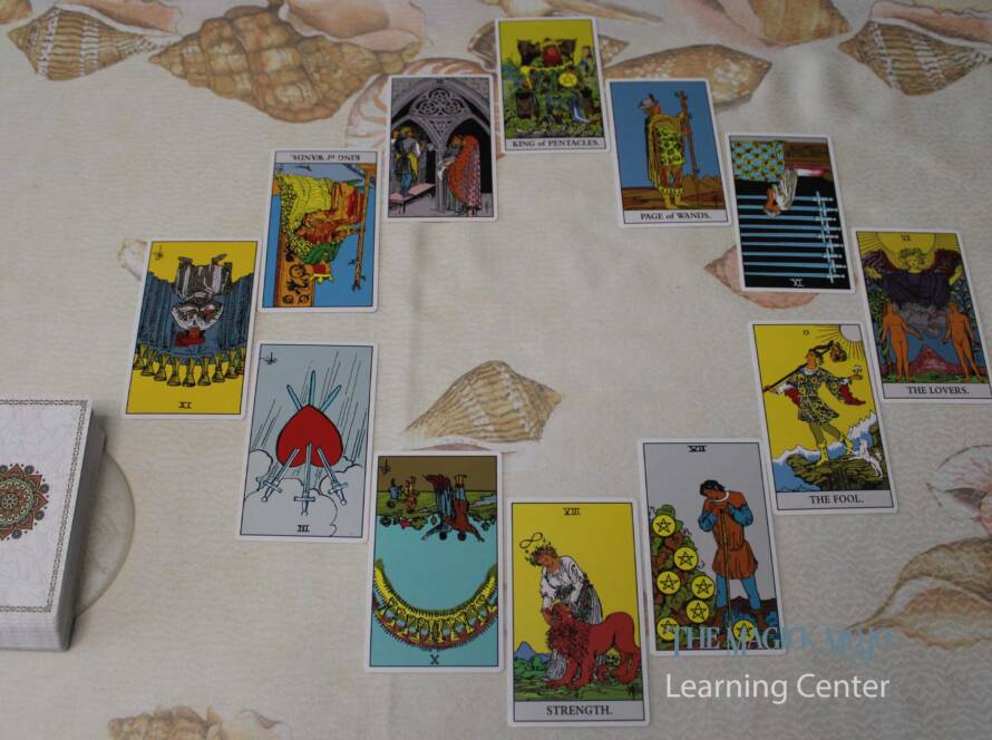 Tarot spread representing the Wheel of the Year, with twelve cards arranged in a circular pattern on a shell-patterned background.