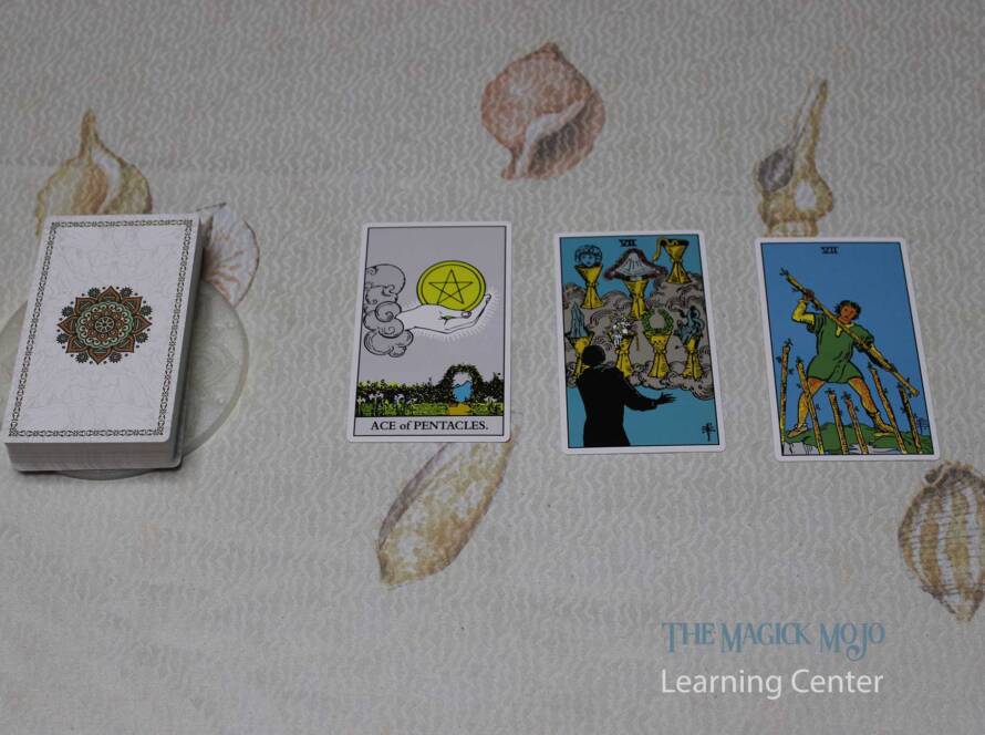 Three Card Spread Tarot reading featuring the Ace of Pentacles, Seven of Cups, and Seven of Wands.
