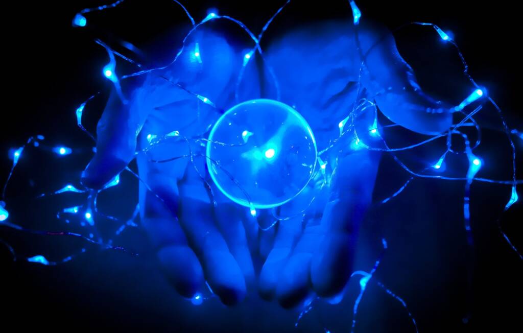 A pair of hands holds a blue ball of chaotic energy, with waves of energy rippling off it.magic
