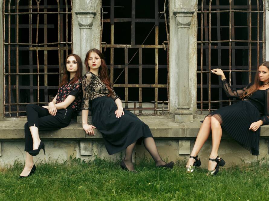 three gorgeous women in black sitting at old church in the city and posing