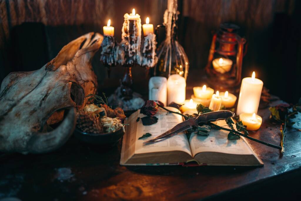A witch's altar with an animal skull, candles, and a ritual book