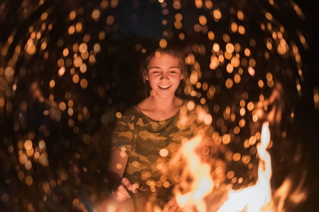 Happy young woman sitting around a bonfire during a modern Beltane celebration
