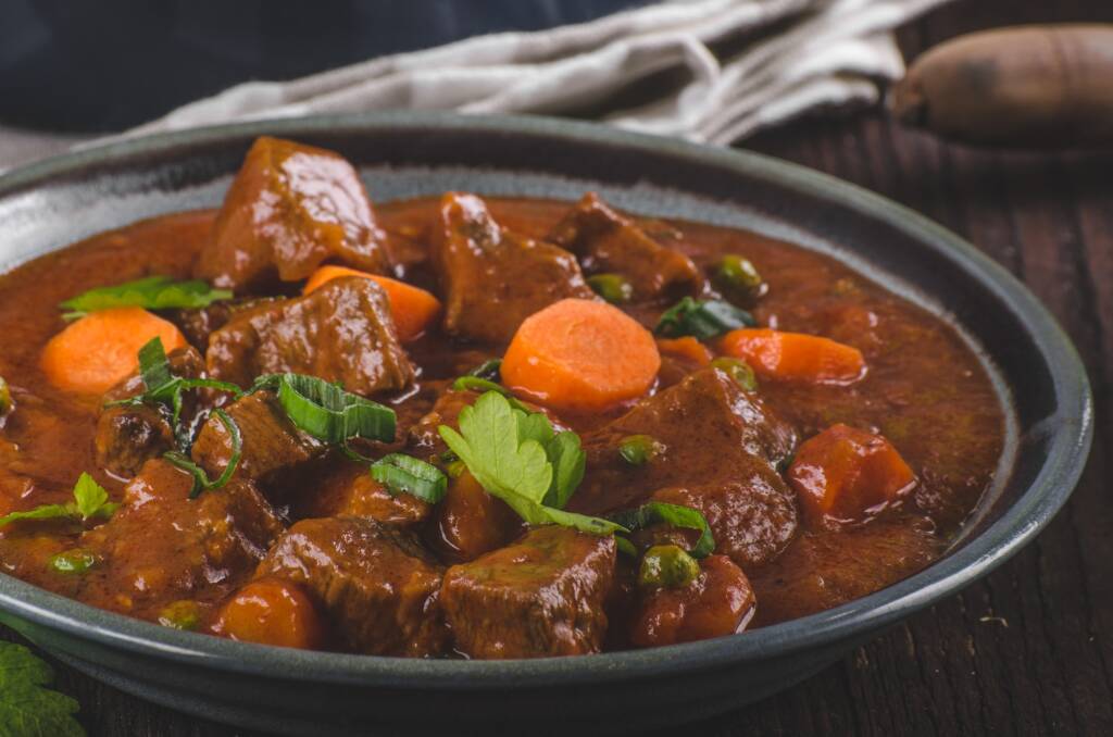 A bowl of hearty beef stew with chunks of tender meat, potatoes, and carrots in a rich, savory gravy