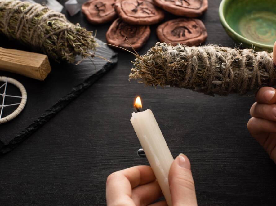 Shaman holding a candle and smudge stick near a witchcraft altar