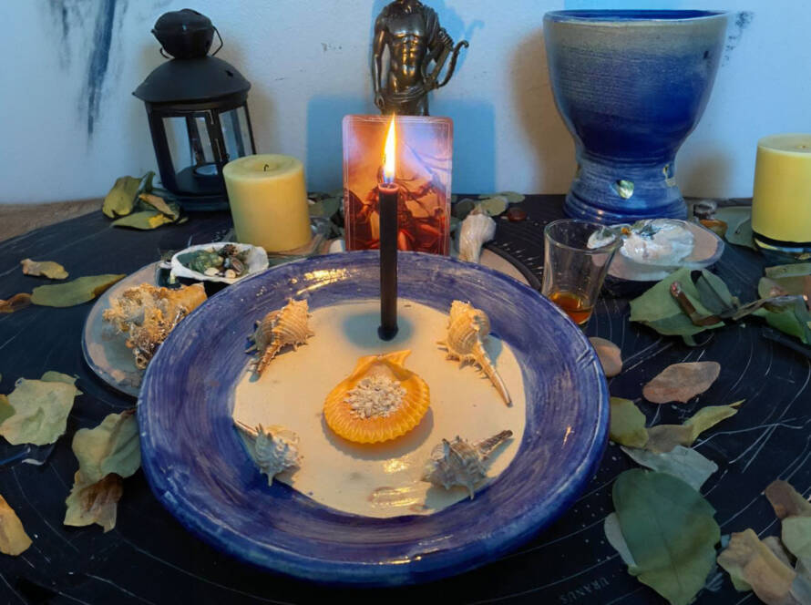 Altar setup with black candle, seashells, and ritual items for a spell