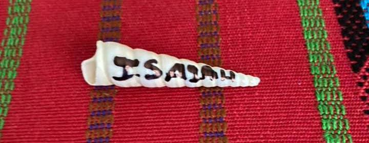 Customized auger seashell with the name "Isaiah" inscribed on a red woven background.