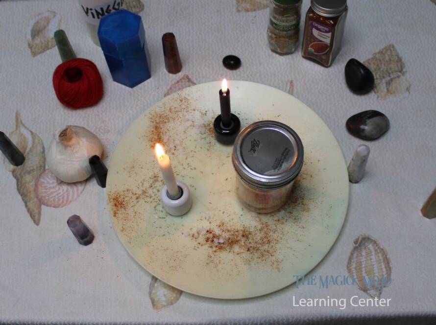 Spellcasting altar with candles, jar, and magical ingredients for a binding spell.