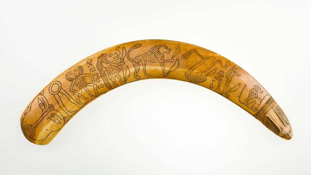 Ancient Egyptian apotropaic wand made from hippopotamus tusk, featuring carved figures of deities and animals.