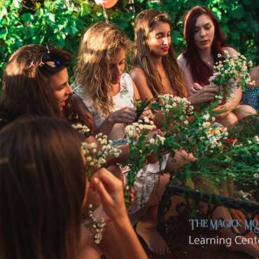 Women celebrating Litha by making flower crowns together outdoors.