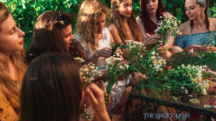 Women celebrating Litha by making flower crowns together outdoors.