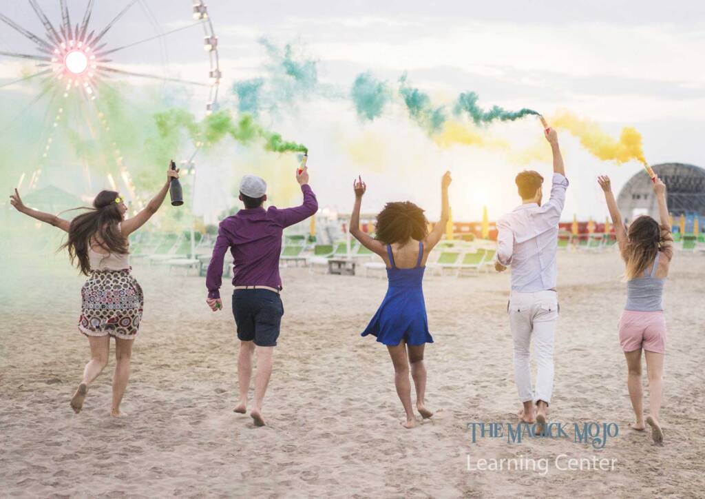 Friends celebrating Litha outdoors with colored smoke on a beach.